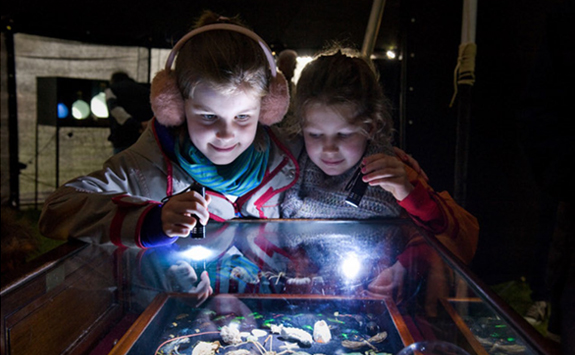 Children looking at exhibition cabinet with artworks 